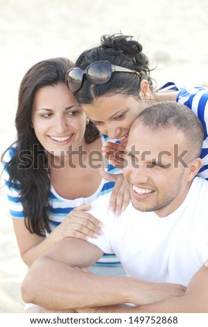 Two beautiful girls teasing a shy man at the beach