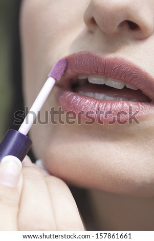 Close up of woman lips while putting on lip gloss