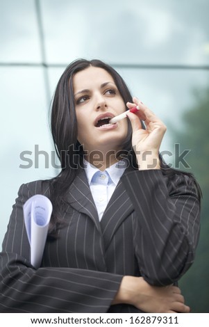 Business woman thinking with a pen in her mouth