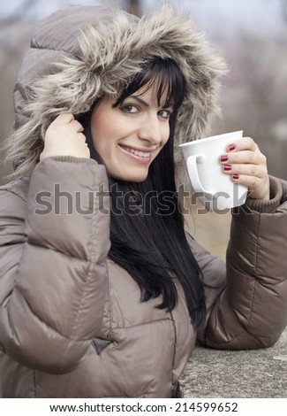 Beautiful young woman holding a mug outdoors