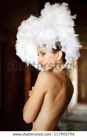Portrait of beautiful girl with feathers on her head in a dark room