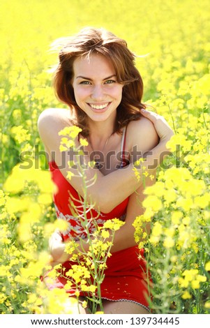 Happy girl enjoying the nature on a sunny day in the flowering yellow field