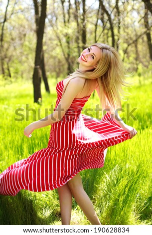 Adorable summer young woman in long red dress, carefree dancing enjoying nature