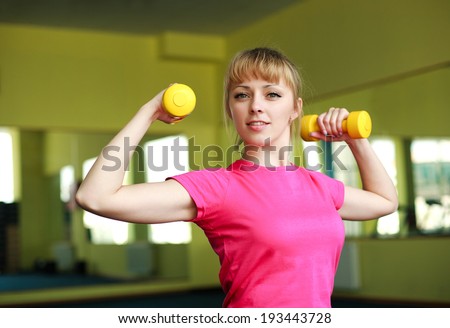 Sporty girl doing exercise with dumbbells in the gym