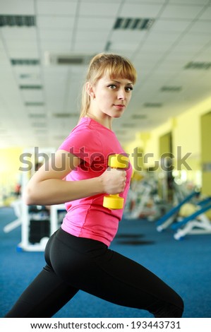 Sporty girl doing exercise with dumbbells in the gym