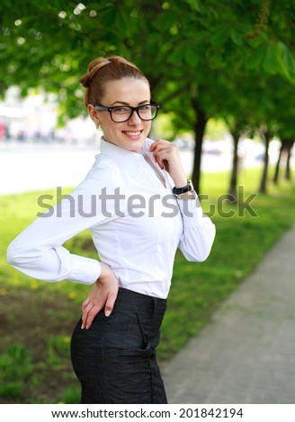 Happy business lady in white shirt and glasses, in a green park