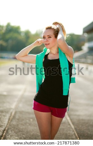 Young sporty woman in the morning with headphones on treadmill outdoors