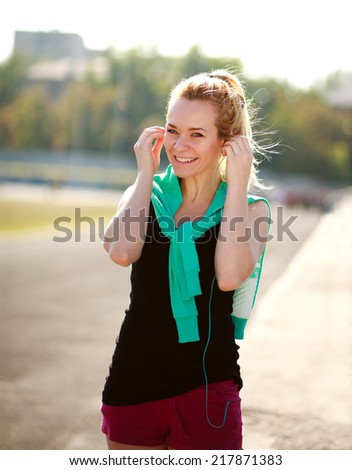 Young sporty woman in the morning with headphones on treadmill outdoors