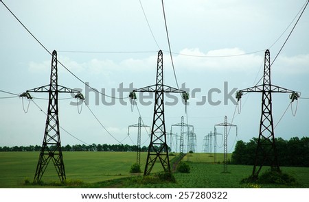 Pillars of line power electricity on green field, beyond the horizon