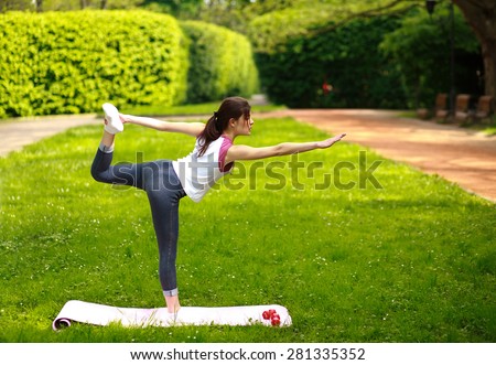 Sportive young woman stretching, doing exercises balancing in yoga pose