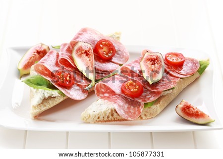 Two baguettes with lettuce, salami and fresh figs - stock photo