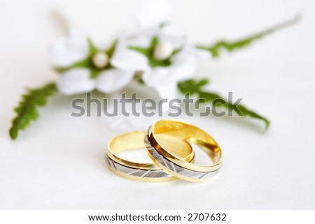 stock photo Wedding rings with small flower on white background