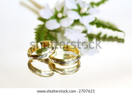 stock photo Wedding rings with small flower on white background