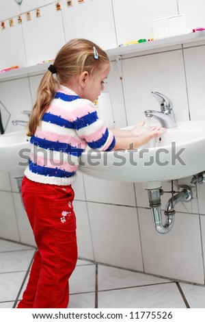 Small girl washing her hands in the bathroom