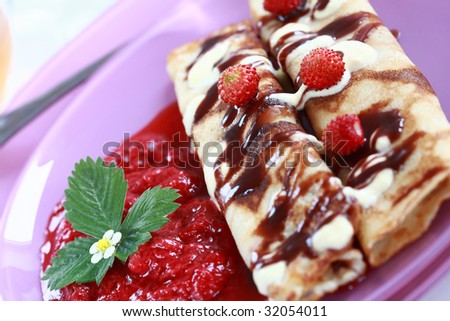 Delicious crepes with strawberry sauce and chocolate