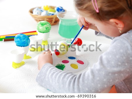 Cute little girl painting Easter eggs