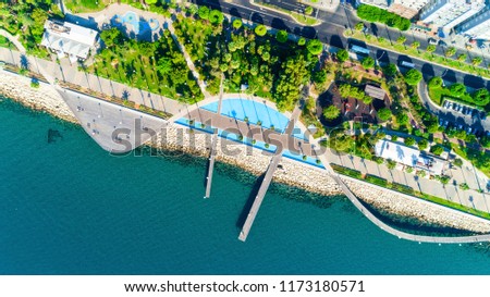 Aerial view of Molos Promenade park on coast of Limassol city centre,Cyprus. Bird\'s eye view of the jetty, beachfront walk path, palm trees, Mediterranean sea, piers, urban skyline and port from above