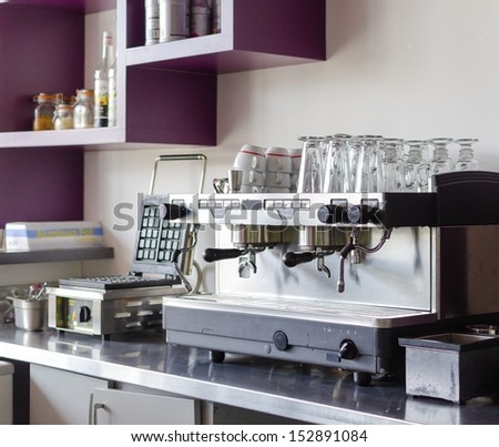 A Professional Espresso Coffee Maker, Ideal For Cafes And Bars. Stored Over It Are Late Glasses And A Waffle Maker Next To It