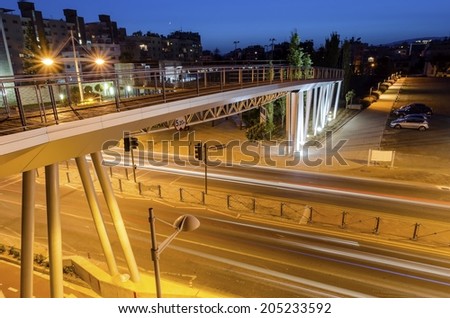 A night view of the seaside bridge  in Limassol, Cyprus. A view of the street, the wooden and glass pedestrian bridge