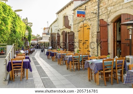 LIMASSOL, CYPRUS - 30 MAY 2014: An alley in the historic medieval city center of Limassol in Cyprus. A view of the cafe, restaurant, cypriot taverna, tables and the souk leading to the castle square