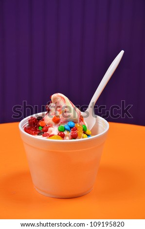 A colorful frozen yogurt treat with a spoon in it.