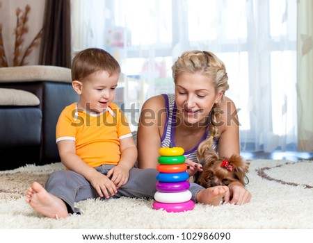mother, child boy and pet dog playing toy together indoor