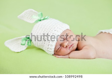 Funny sleeping newborn child. Bunny cap on head of girl.