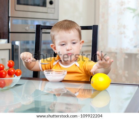 cute little boy eating healthy food at kitchen