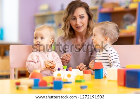 Children toddlers with kindergarten teacher is playing with montessori material. Learning through experience concept, gross and fine motor skills.