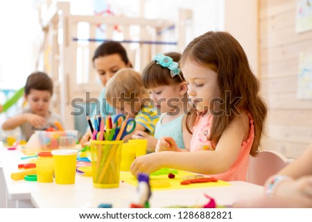 kindergarten children doing arts and crafts with teacher in day care centre