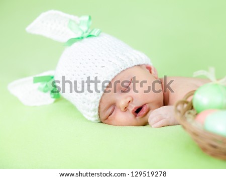 adorable baby dressed in Easter bunny cap with eggs
