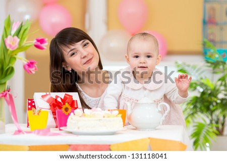 Little girl and mother celebrate birthday holiday. Focus at baby.