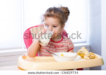 kid girl eating corn flakes with milk