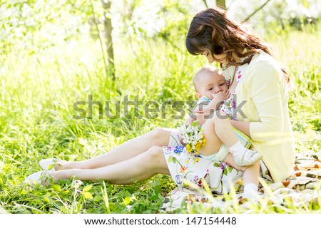 young mother breast feeding her baby outdoors summertime