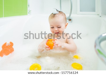smiling baby girl taking bath and playing with toys
