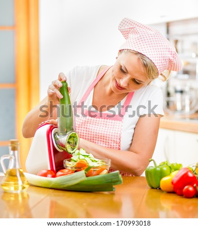 woman cutting vegetables with device in kitchen