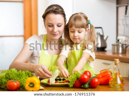 Young Mother And Her Kid Making Vegetable Salad