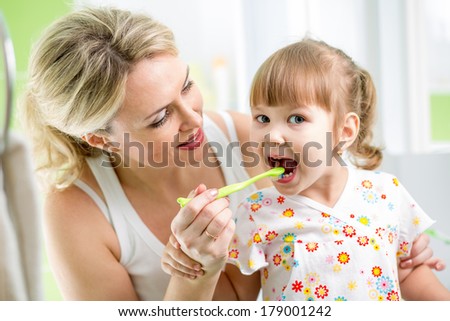 mother teaches kid teeth brushing