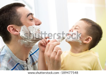 playful father and his son shaving and having fun in bathroom
