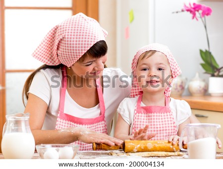 kid girl with her mother cook and roll out the dough