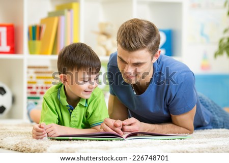 child boy and his dad read a book on floor at home