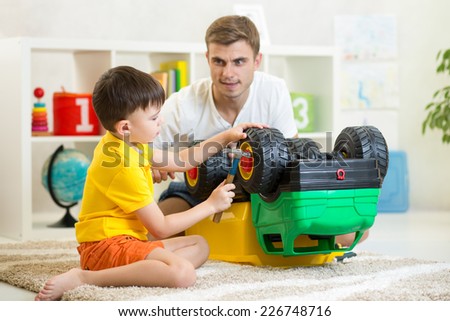 child boy and his dad repair toy car