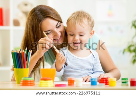mom and kid boy painting together at home