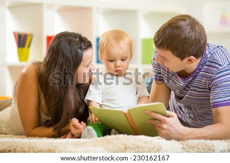 Young parents mom and dad reading children book to baby son