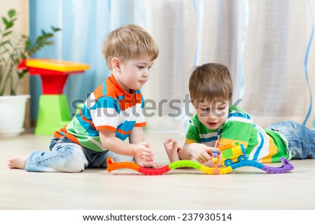 children  playing rail road toy in playroom