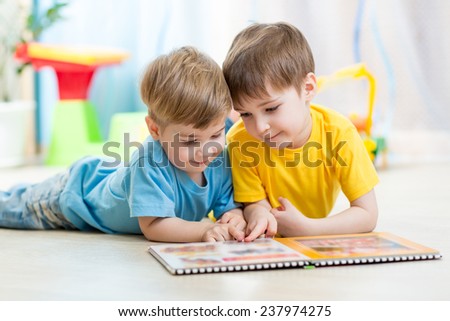 children brothers reading a book on floor indoors
