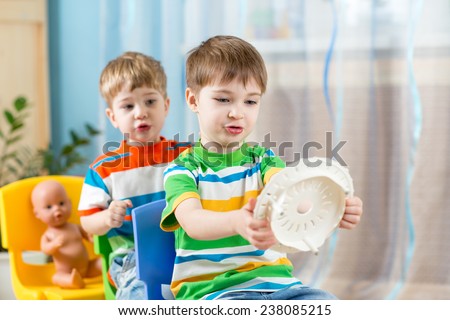 Two kids boys playing role game and riding on carriages made from chairs