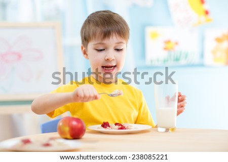 kid boy eating healthy food at home or nursery