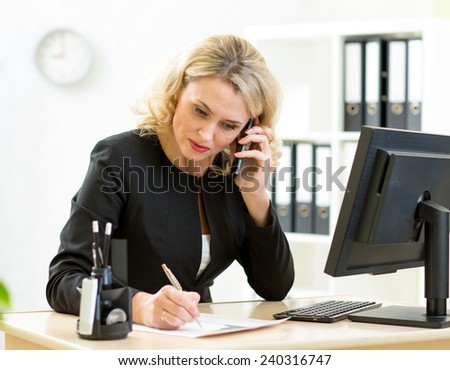 Cute middle-aged businesswoman working at desk in office.