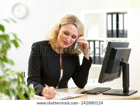Smiling middle-aged businesswoman working  at table in office